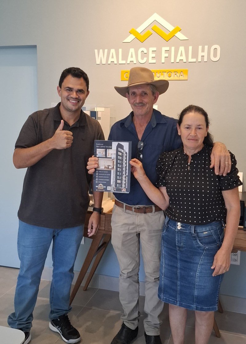 Família comprando apartamento no stand de vendas, segurando o material do empreendimento.