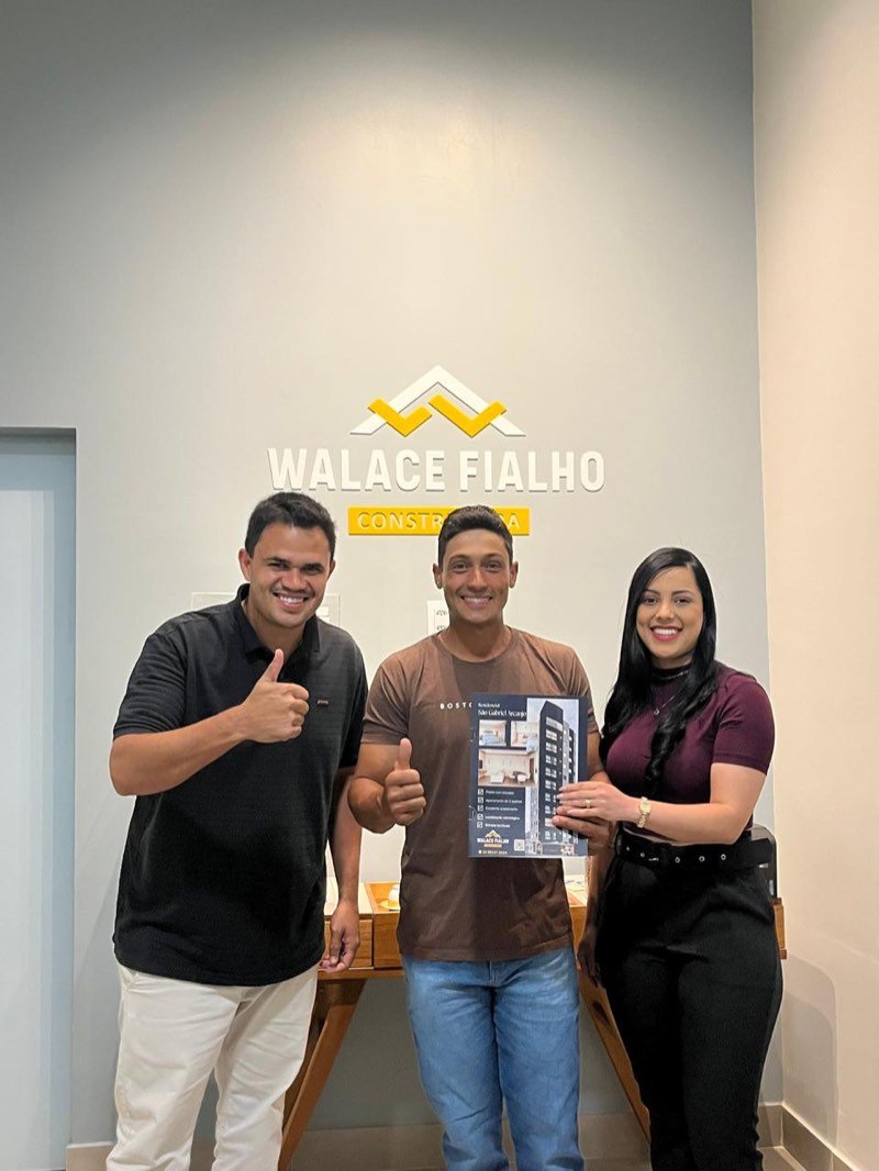Compradores no stand de vendas segurando o material do Residencial São Gabriel Arcanjo.