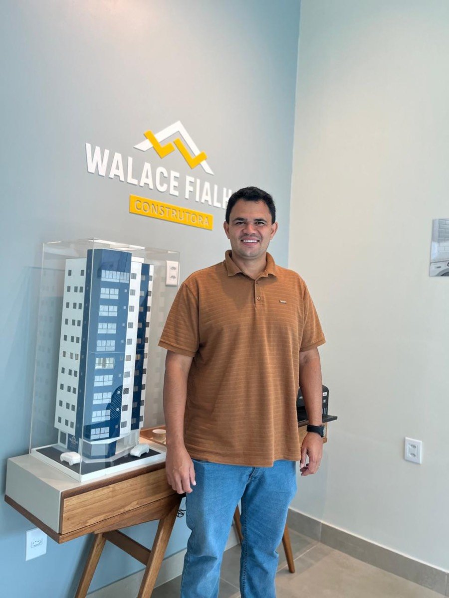 Walace Fialho, engenheiro responsável pela obra, ao lado da maquete do edifício no stand de vendas.